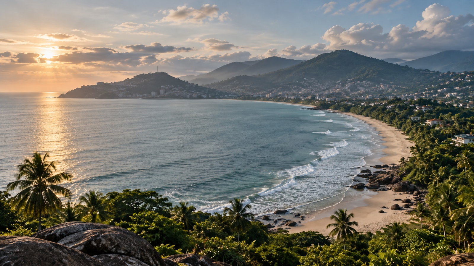 A long sandy bay beneath forested coastal hills.