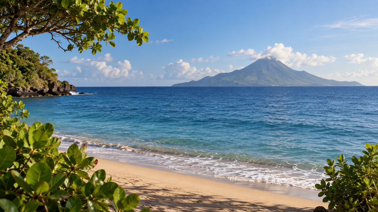 A sandy shore looking across blue water toward a distant volcanic island.
